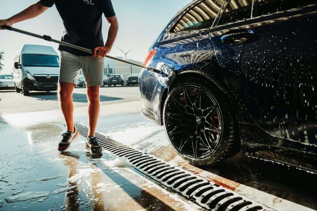a man is washing a car with a hose